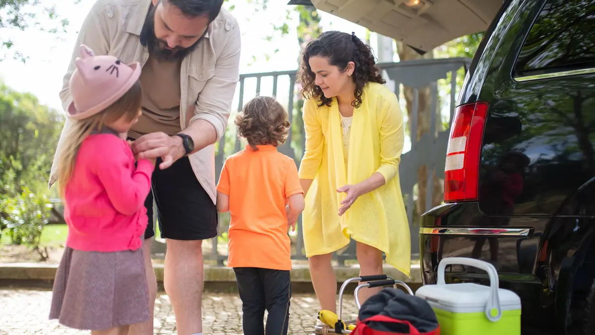 Família colocando as malas no porta-malas do carro antes de viajar
