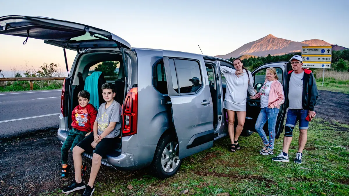 Família com dois filhos ao lado do carro durante uma viagem pela estrada